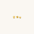 Close up of gold stud earrings on a white background