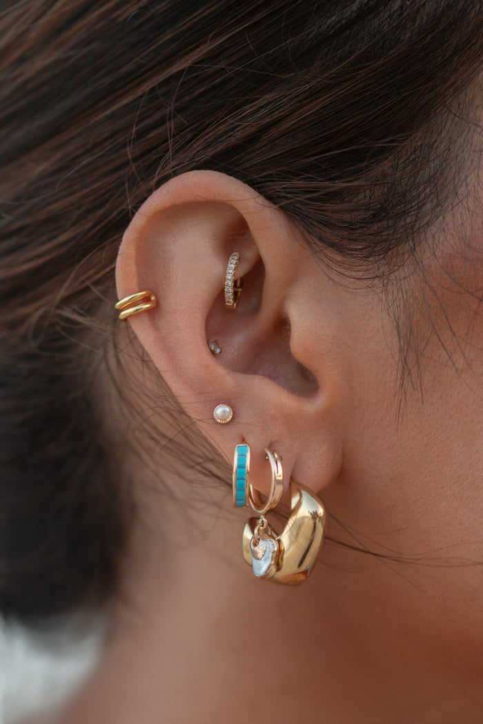 Close-up of an ear with multiple gold crystal earrings