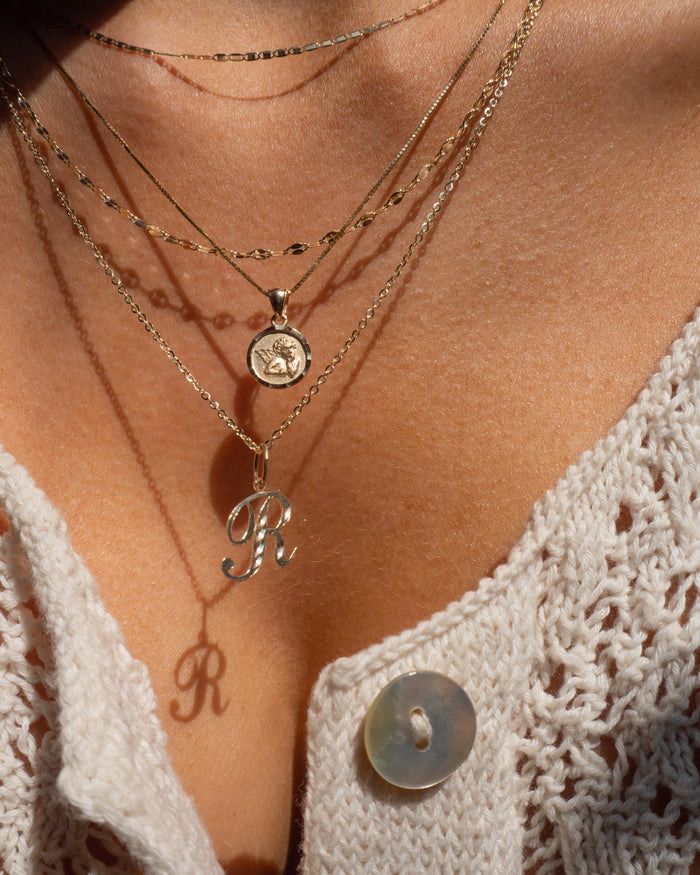 Model wearing the 14k gold Cherub necklace as part of an everyday stack
