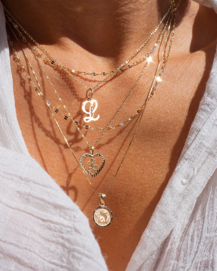 Model wearing the gold Cherub pendant necklace layered with dainty chains