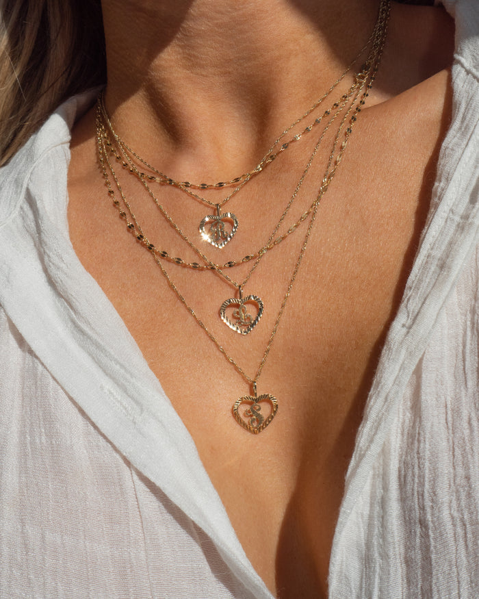 Model wearing the Corazon heart initial necklace on a fine gold chain