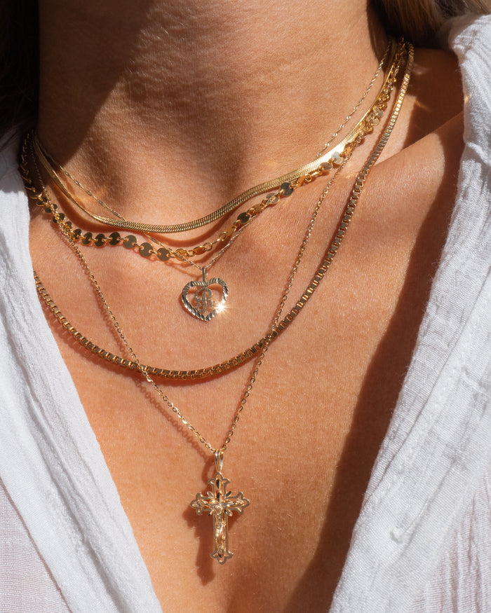 Model wearing the gold Corazon initial necklace layered with dainty chains