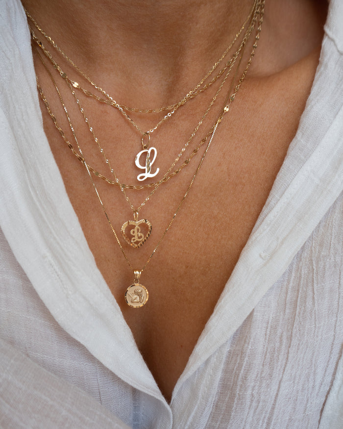 Model wearing the solid gold Corazon initial pendant near the collarbone