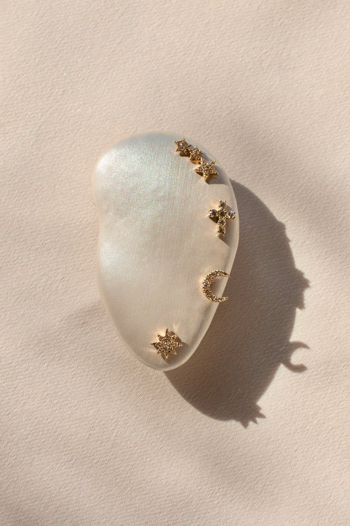 A model ear prop with multiple gold and crystal stud earrings