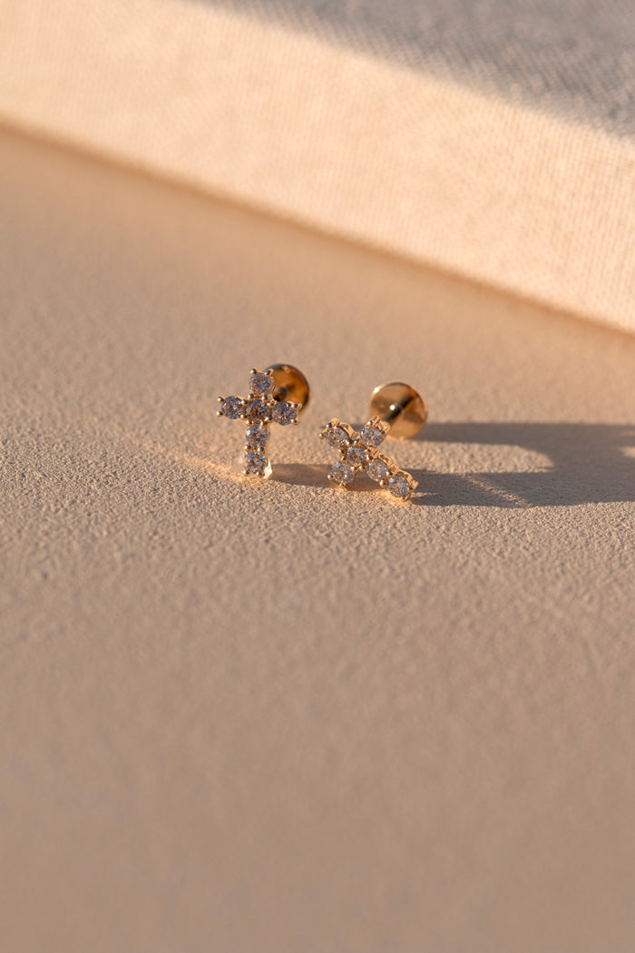A pair of stone cross studs on a neutral surface