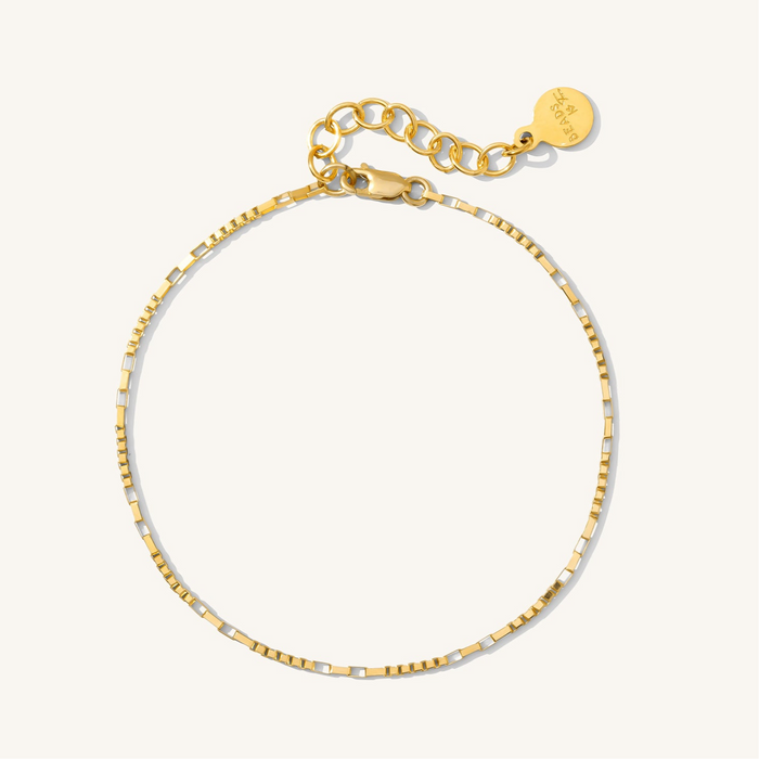 Close up of a dainty gold chain bracelet on a white background
