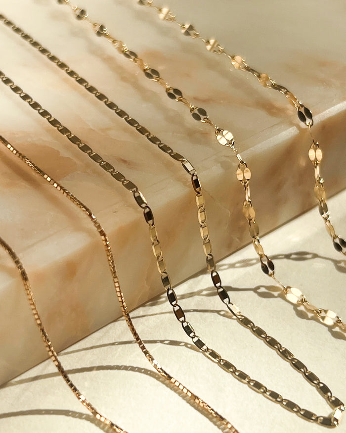 Model wearing the 14k Disco Tile chain layered with dainty gold necklaces