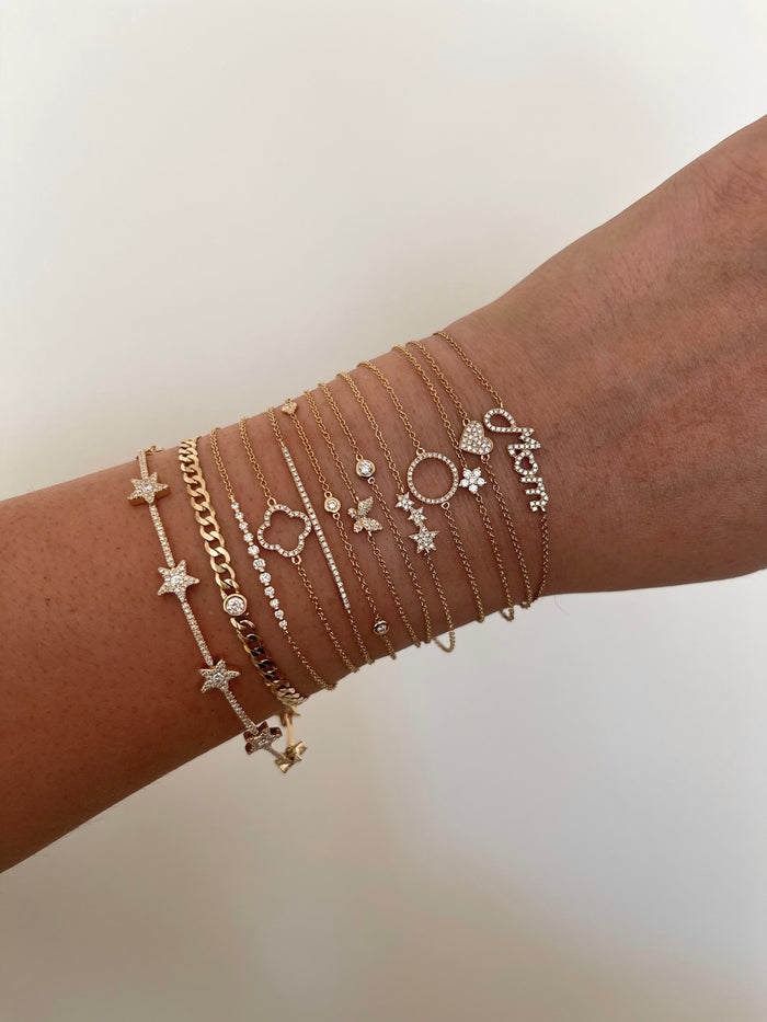 A wrist with dainty gold and diamond bracelets on a white background