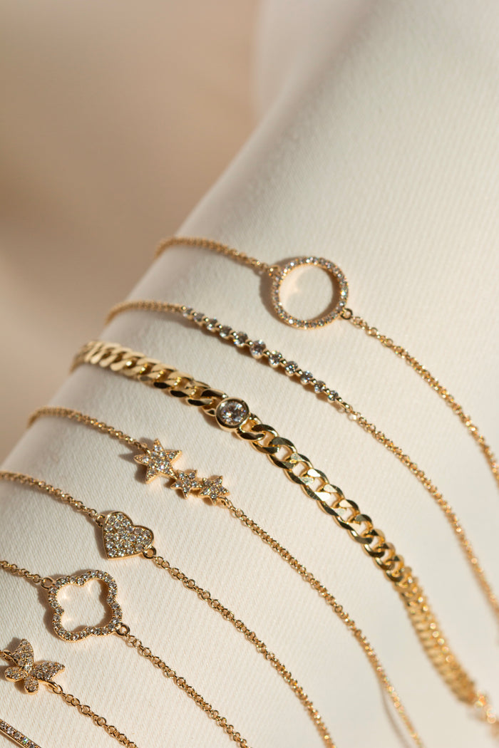 Close up of gold and diamond bracelets on a white jewelry display cuff