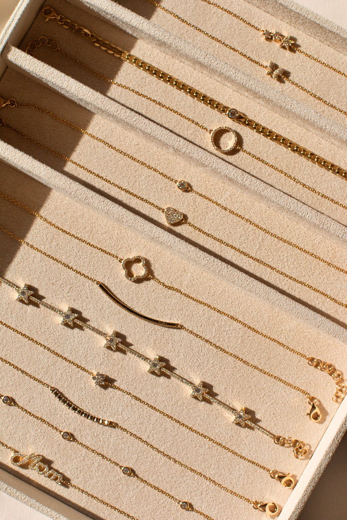 A tan jewelry tray with gold and diamond bracelets laid out