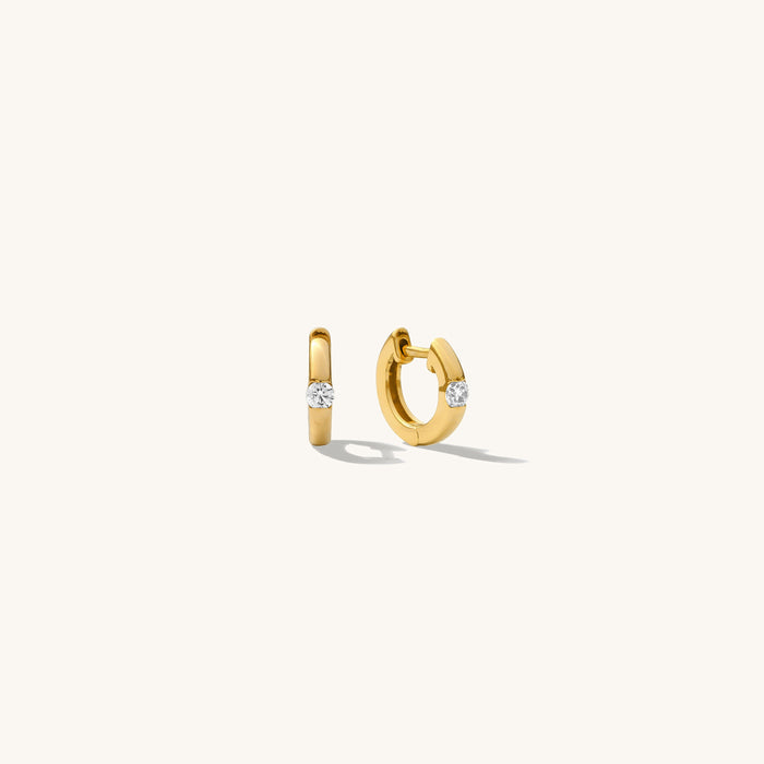 Close up of gold hoops with stones on a white background