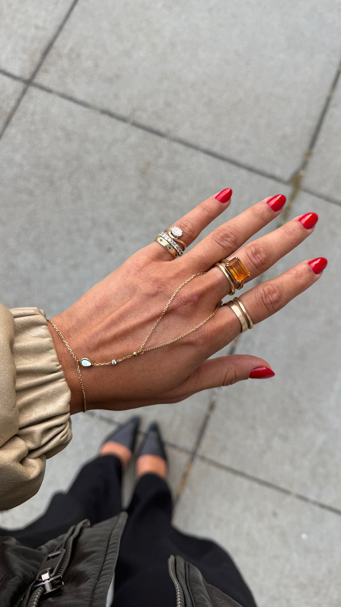 Delicate gold hand chain accented with luminous mother-of-pearl detailing