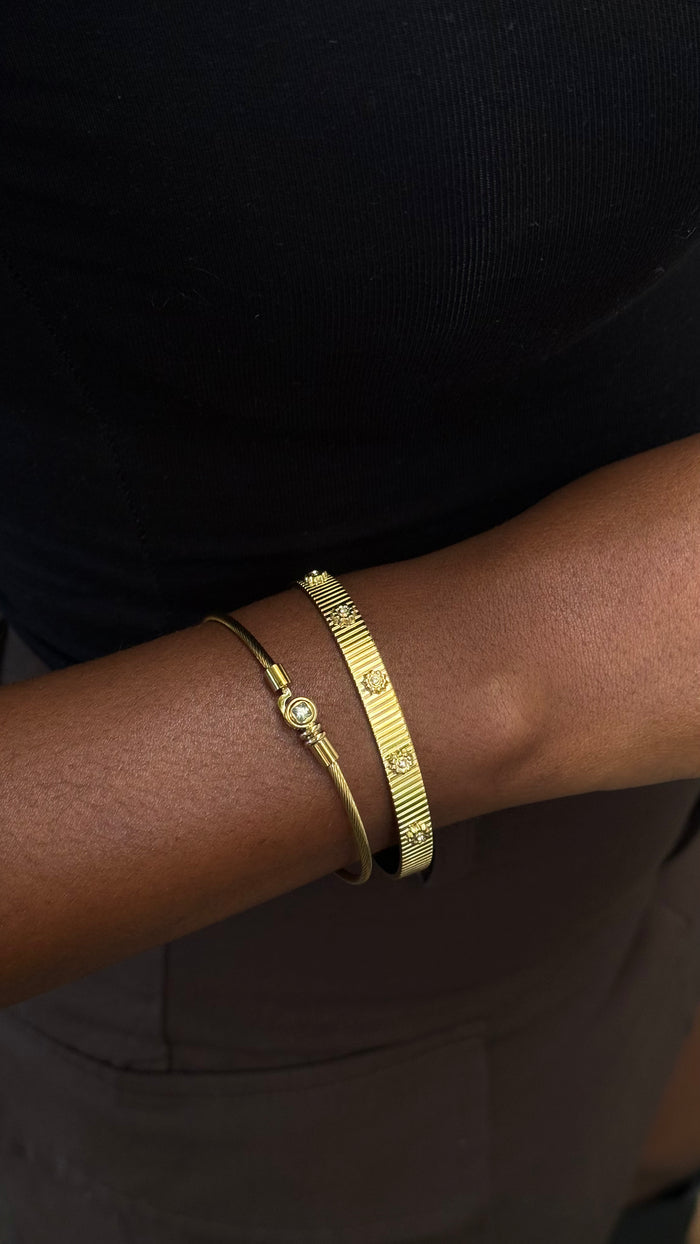 Close up of a wrist with gold bracelets on a dark background