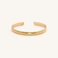 Close up of a gold cuff bracelet on a white background