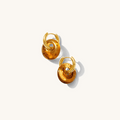 Close up of gold huggie earrings with removable resin charms on a white background