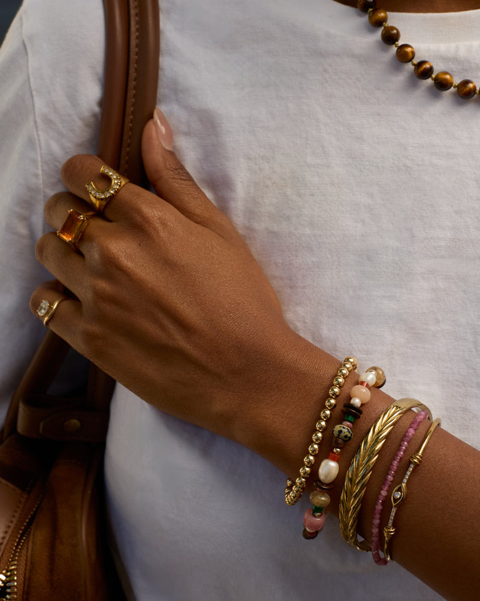 Hand with multiple bracelets and rings on a white background