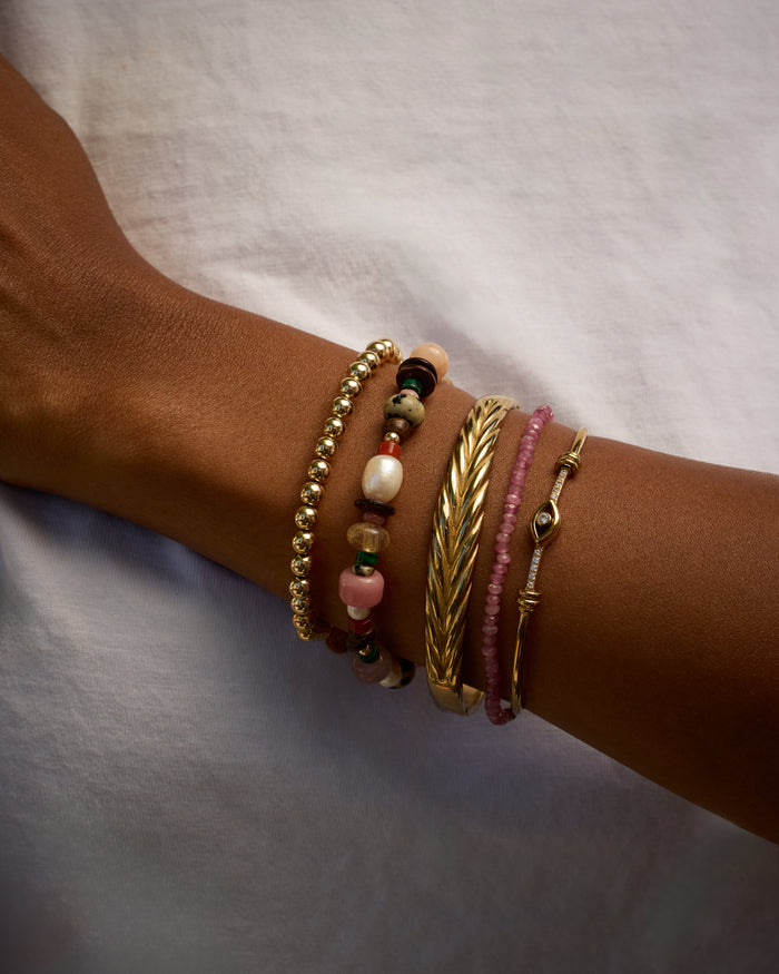 Close-up of a wrist wearing multiple bracelets on a neutral background