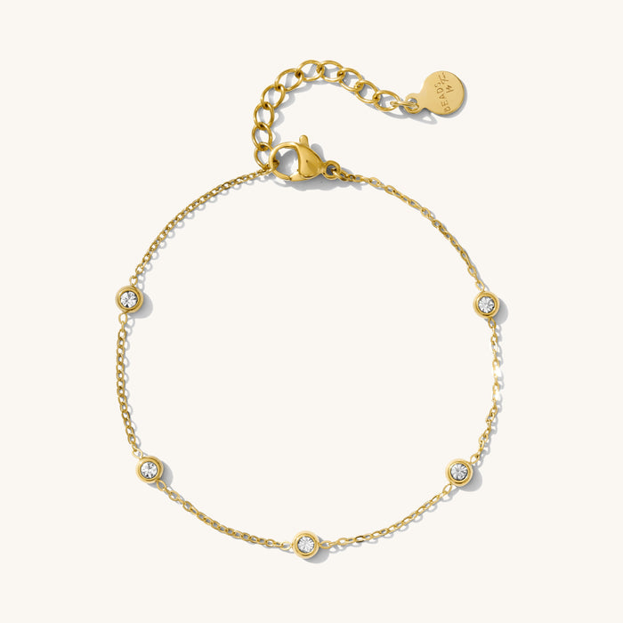 Close up of a gold chain bracelet with stone accents on a white background