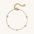 Close up of a gold chain bracelet with stone accents on a white background