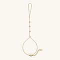 Close up of gold hand chain with stone accents on a white background
