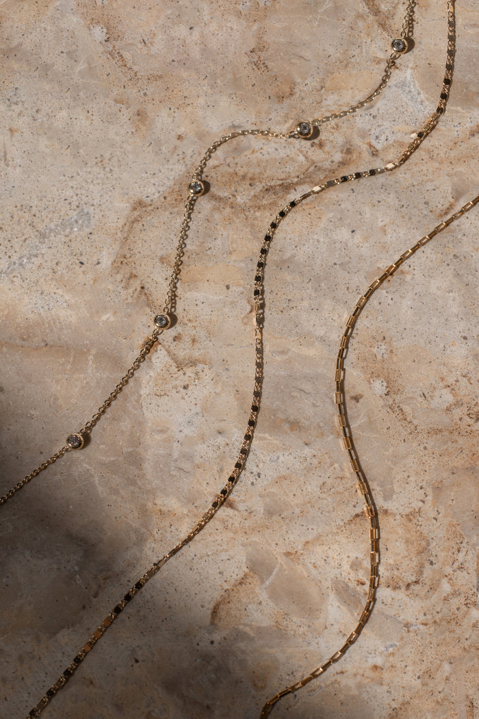 Gold chain necklace on a textured stone surface