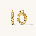 Close up of twisted gold hoop earrings on a white background