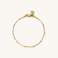 Close up of a gold chain bracelet on a white background