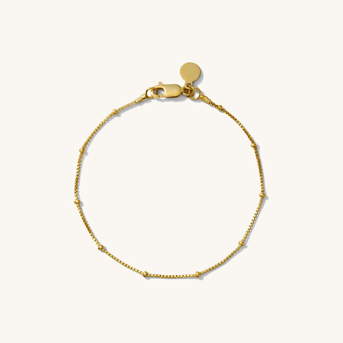 Close up of a gold chain bracelet on a white background
