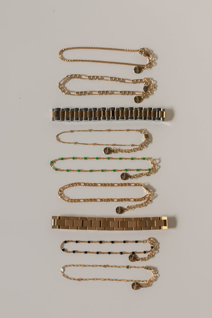 Flatlay of various gold bracelets on a white background