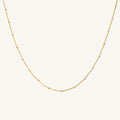 Close up of the gold Azin bead and cable chain necklace on a white background