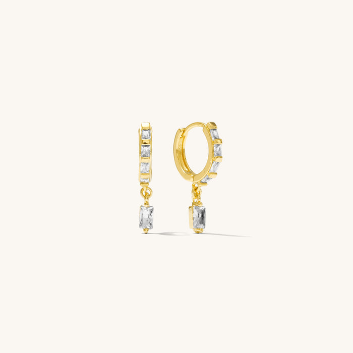 Close up of gold huggies with crystal accents on a white background