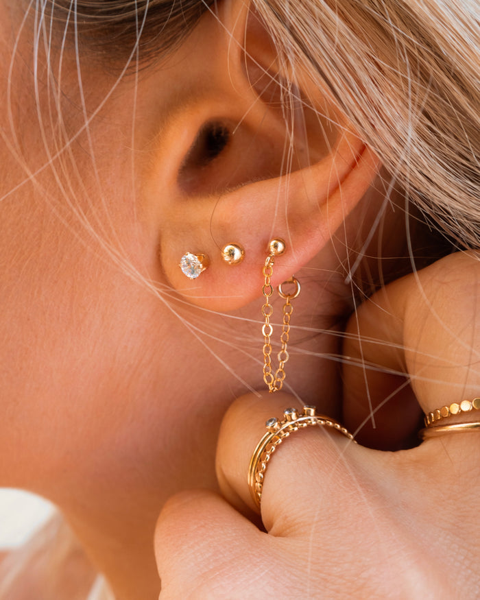 Close-up of an ear with multiple gold stud earrings