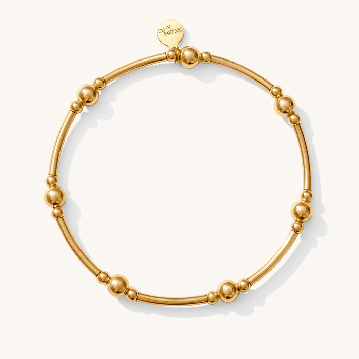 Close up of a gold bead bracelet on a white background