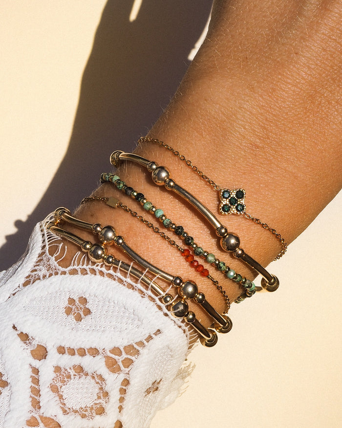 A wrist with a lace sleeve and assorted colored gold bracelets