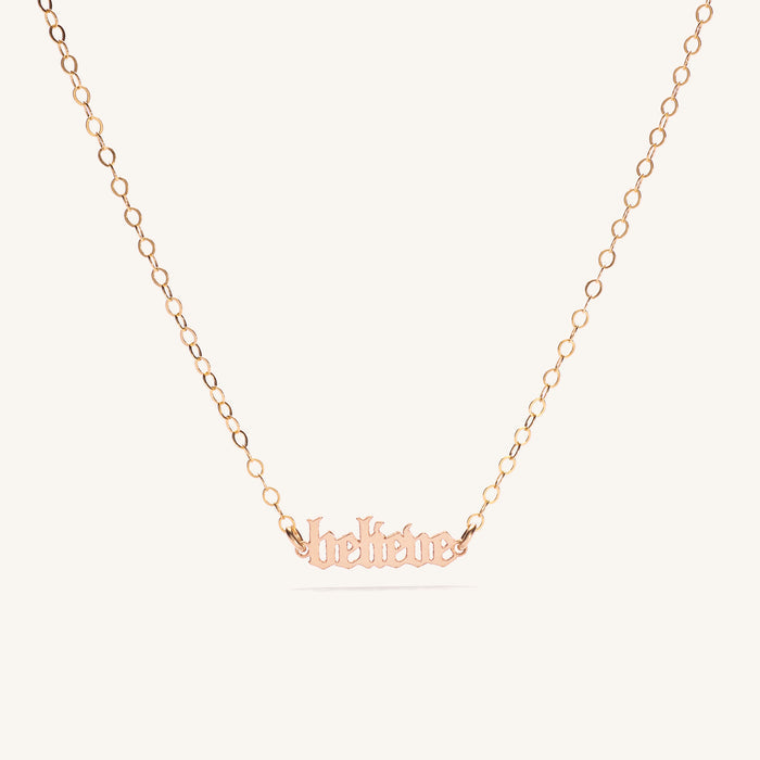 Close up of the gold Believe mini affirmation necklace on a white background