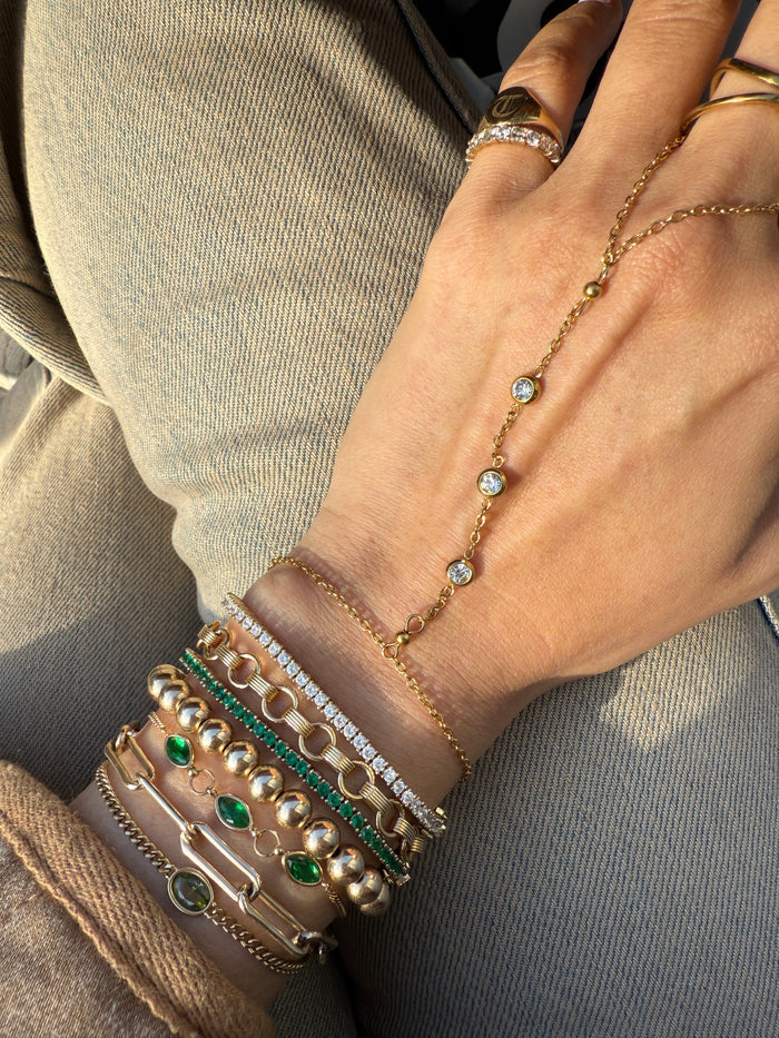 Close up of a hand with assorted gold and stone bracelets and rings
