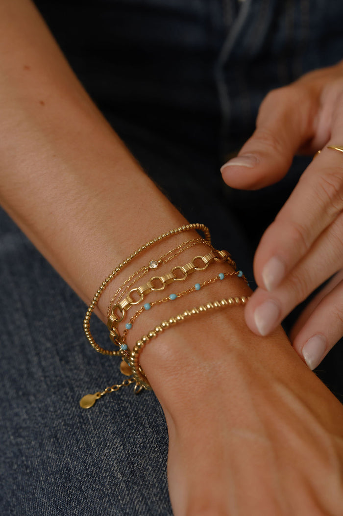 Close up of a wrist with gold bracelets
