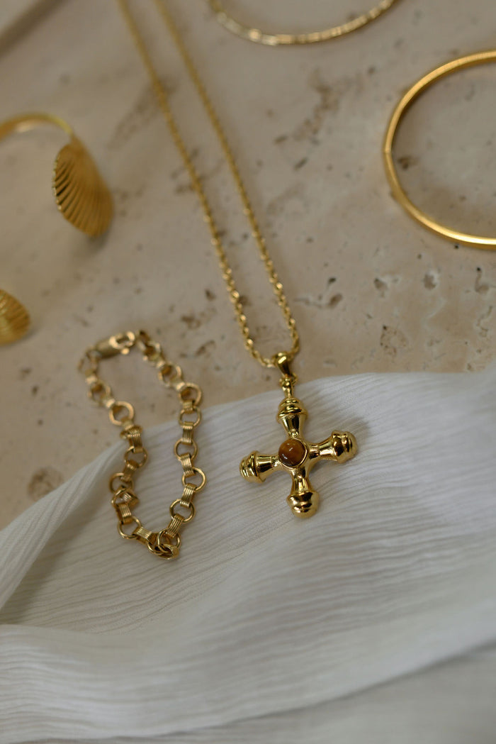 Close up of a gold bracelet and necklace on a stone surface
