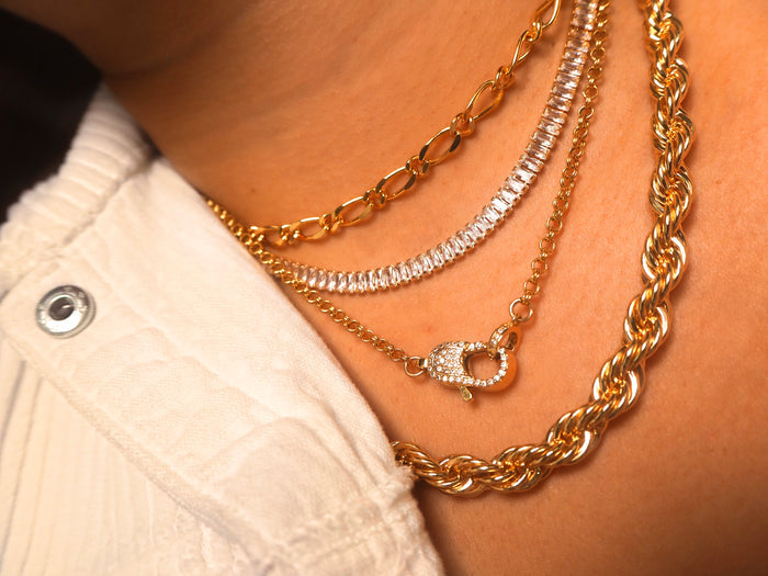 The Bellini tennis necklace worn layered with other gold chains
