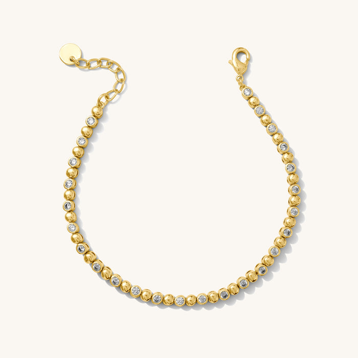 Close up of a gold bracelet with stone accents on a white background