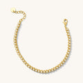 Close up of a gold bracelet with pearl details on a white background