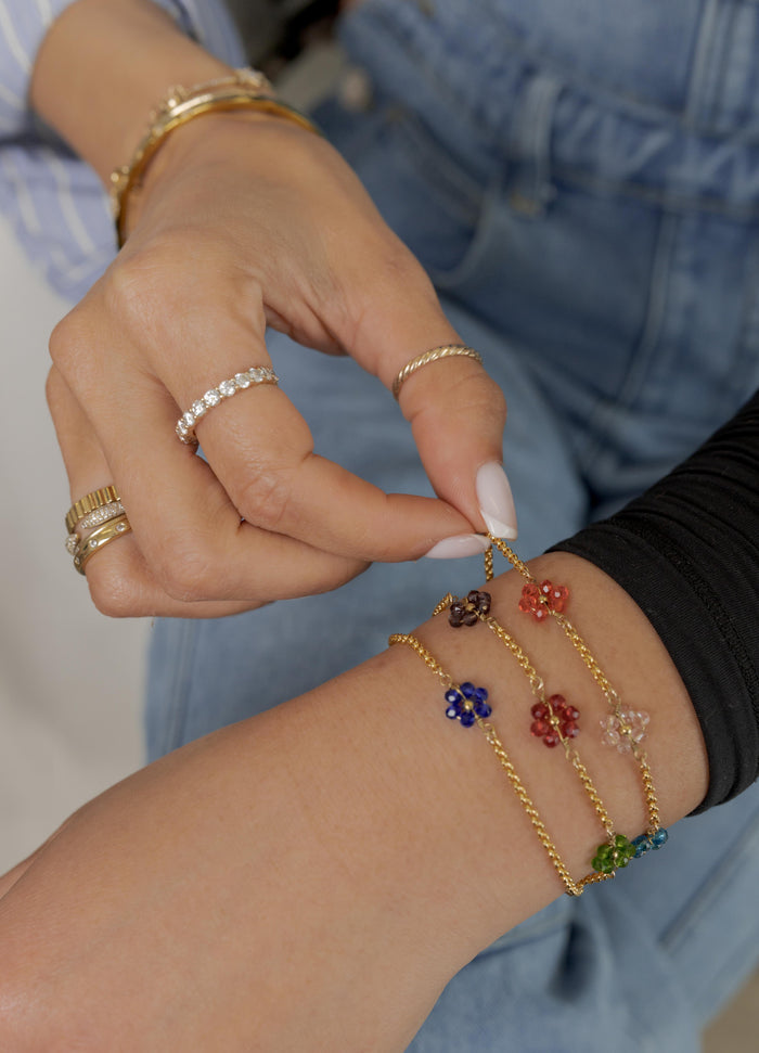 Close up a person wearing a black shirt, blue jeans, and various stone bracelets and rings