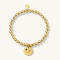 Close up of a gold bracelet with charm on a white background