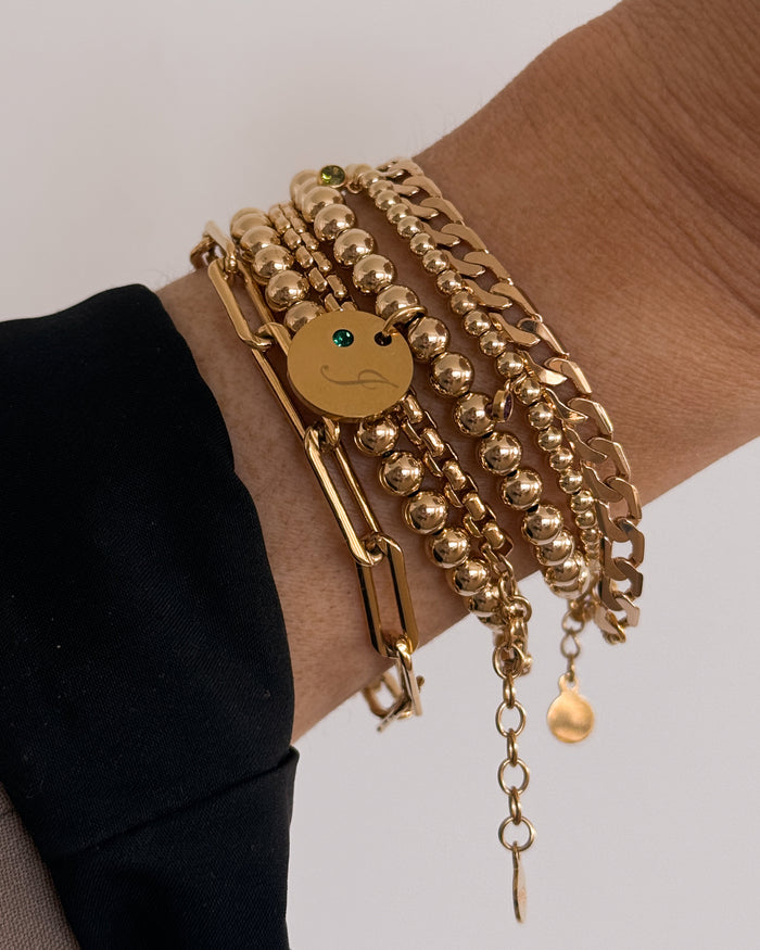 Close up of a wrist in a black sweater with assorted gold bracelets