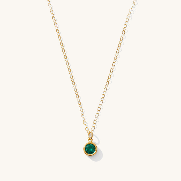 Close up of the gold birthstone necklace on a white background