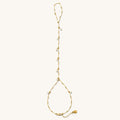 Close up of gold hand chain with pearl accents on a white background