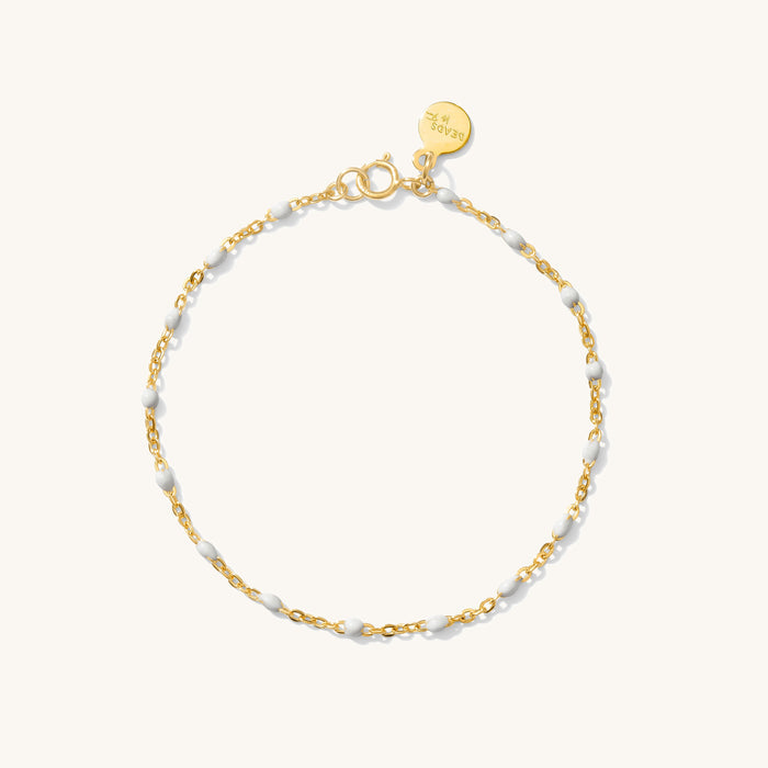 Close up of gold bracelet with red bead accents on a white background