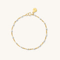 Close up of gold bracelet with red bead accents on a white background