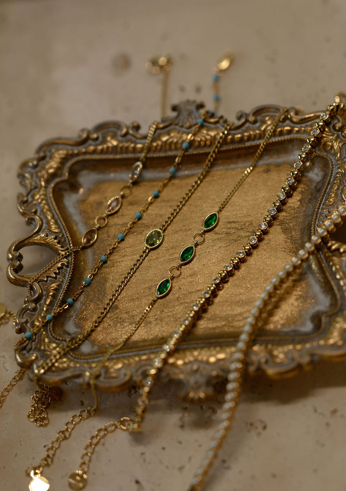 Gold bracelets with stone accents resting on a gold tray