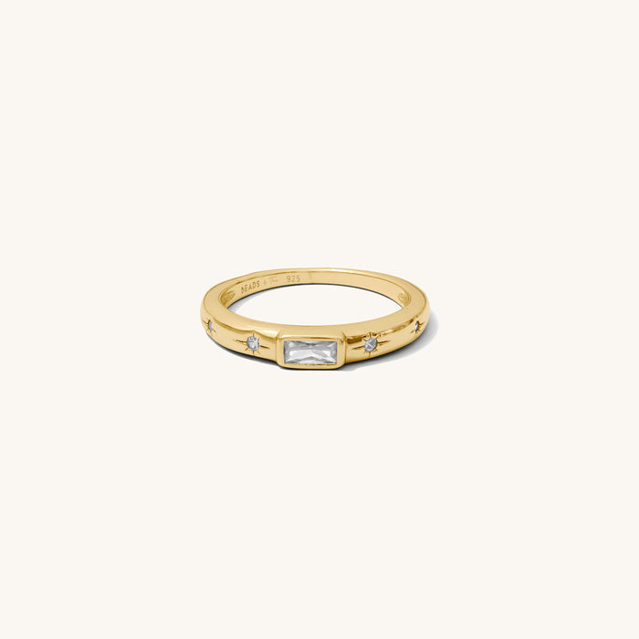 Close up of the gold Celeste emerald cut ring on a white background